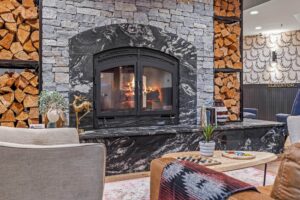 Cozy living room with stone fireplace, stacked firewood, and chess board.