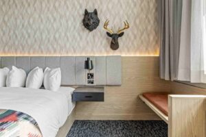 Canmore hotel room with wolf and deer decor, bed, and bench.