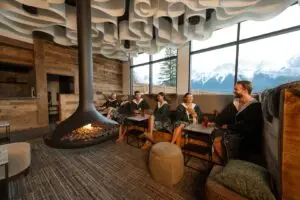 People relaxing in a spa lounge with fireplace and mountain view