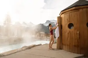 Woman in swimsuit drying off with towel by outdoor spa pool